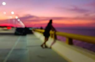 beau fond de lumières bokeh au crépuscule, personnes debout sur les balustrades de mer regardant la mer au coucher du soleil. ciel violet photo