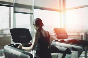 femme de sport asiatique courant sur tapis roulant dans un club de fitness. entraînement cardio. mode de vie sain, gars s'entraînant dans la salle de gym. concept de course sportive photo