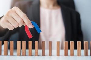 main de femme d'affaires tenant l'aimant et tirant la figure en bois de l'homme du bloc de foule. affaires, gestion des ressources humaines, recrutement, travail d'équipe, stratégie, personnes toxiques et concepts de leadership photo