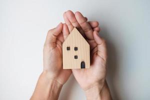main tenant la clé avec le modèle de maison en bois. immobilier, achat et vente, assurance des biens, concepts de contrat de location et de contrat photo