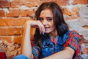 belle jeune femme se tient près du vieux mur de briques. style jeunesse photo