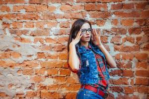 belle jeune femme se tient près du vieux mur de briques. style jeunesse photo