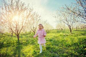 petite fille qui court entre les arbres en fleurs au coucher du soleil. ar photo