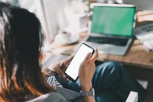 une femme asiatique tient un texte ou un message sur son téléphone portable. une femme d'affaires utilise un smartphone moderne pour naviguer sur le Web, lire des livres électroniques, échanger des actions. photo