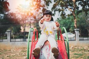 jolie fille asiatique joue dans la cour ou l'aire de jeux de l'école ou de la maternelle. activité estivale saine pour les enfants. petite fille asiatique grimpant à l'extérieur sur l'aire de jeux. enfant jouant sur une aire de jeux extérieure. photo