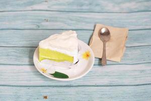 gâteau à la crème de noix de coco sur le dessert maison en bois bleu avec cuillère et papier de soie photo