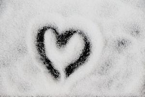 en forme de coeur sur sucre blanc sur fond noir. symbole d'amour dessiné à la main pour la saint-valentin. photo