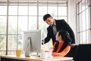 jeune homme d'affaires asiatique adulte enseignant le travail à une femme au bureau le jour photo