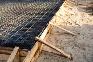 les raccords en fer sur un coffrage en bois avec des tuyaux posés sont la base pour couler les fondations de la maison avec une dalle de béton. construction de chalets, conception, communication d'ingénierie. photo