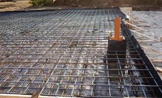 les raccords en fer sur un coffrage en bois avec des tuyaux posés sont la base pour couler les fondations de la maison avec une dalle de béton. construction de chalets, conception, communication d'ingénierie. photo