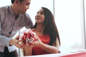 se concentrer sur la boîte cadeau rouge actuelle. homme couple main tenir une surprise romantique le donner à sa petite amie le jour de la saint-valentin. photo