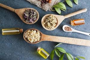 cuillères en bois avec herbes médicinales séchées et bouteilles vintage avec essence. thés médicinaux et teintures comme médecine alternative photo