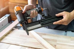 charpentier charger des clous dans un pistolet à clous, concept de menuiserie de restauration de meubles. mise au point sélective photo
