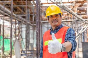 homme ouvrier avec le pouce vers le haut sur un chantier de construction flou, concept réussi photo