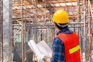 homme ingénieur vérifiant et planifiant le projet sur le chantier de construction, homme tenant un plan de mise au point sélective sur papier photo