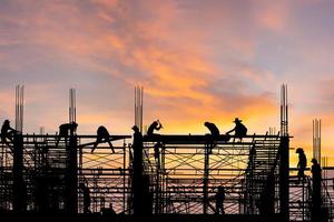 silhouette d'ingénieur et d'ouvrier sur chantier, chantier de construction au coucher du soleil le soir photo