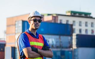 Cheerful factory worker man in hard hat smiling avec les bras croisés en signe de succès photo