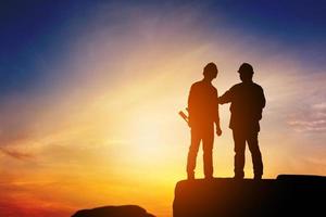 silhouette d'ingénieur et de travailleur debout sur la pierre en pensant au coucher du soleil du projet en soirée. photo