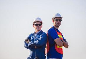 joyeux ouvrier d'usine équipe d'hommes dans un casque souriant avec les bras croisés en signe de succès arrière-plan flou photo