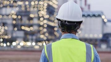 vue arrière, ingénieur senior portant un casque et un gilet de sécurité a sur fond de centrale électrique. photo