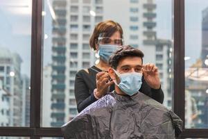 jeune homme se faisant couper les cheveux par un coiffeur, coiffeur utilisant des ciseaux et un peigne, nouveaux concepts normaux photo