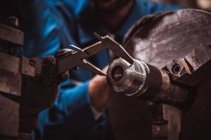 ingénierie de l'industrie portant la machine de meulage de tour d'exploitation de contrôle uniforme de sécurité travaillant dans l'usine de l'industrie. photo