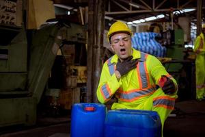 l'industrie des ingénieurs portant un uniforme de sécurité, des gants noirs, un masque à gaz se sent étouffé lors de la vérification du réservoir de produits chimiques dans le travail en usine de l'industrie. photo