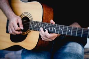 photo d'un guitariste, d'un jeune homme jouant de la guitare assis dans un jardin naturel, concept musical