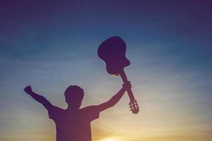 silhouette d'un guitariste dans l'ombre à la lumière du coucher du soleil, concept de silhouette. photo