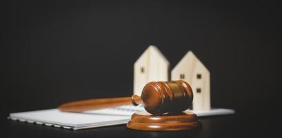 ancien marteau de juge en bois avec mini modèle de maison en bois à partir d'un modèle sur table en bois, planification d'achat immobilier, planification d'achat de propriété et choix du meilleur concept de passif financier. photo