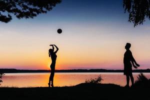 couple en jeu au coucher du soleil au bord du lac photo