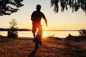 garçon sur un vélo au coucher du soleil photo