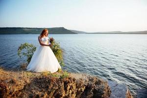 mariée avec un bouquet de fleurs près de l'eau photo