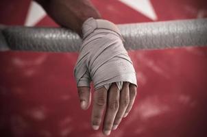 gros plan de la main du boxeur s'appuyant sur des cordes sur un ring de boxe. photo