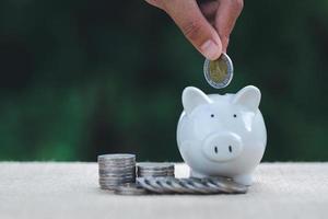 une femme met des pièces dans une tirelire. concept d'épargne pour la comptabilité financière. l'économie, l'investissement, la croissance des entreprises et la richesse. photo