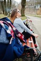 jeune fille fumant une cigarette à l'extérieur assis sur un banc. concept de dépendance à la nicotine chez les adolescents. photo