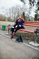 jeune fille fumant une cigarette à l'extérieur assis sur un banc. concept de dépendance à la nicotine chez les adolescents. photo