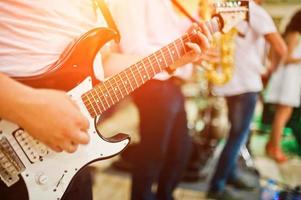 homme jouant de la guitare électrique contre le groupe. photo