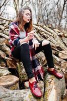 jeune fille fumant une cigarette à l'extérieur des souches en bois de fond. concept de dépendance à la nicotine chez les adolescents. photo
