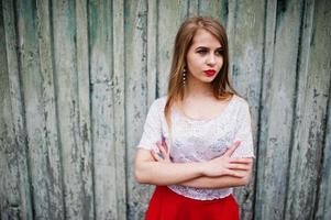 portrait de belle fille aux lèvres rouges sur fond de bois, porter une robe rouge et un chemisier blanc. photo