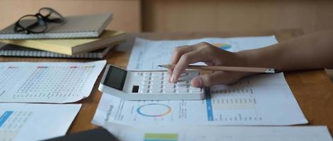 femme travaillant sur un projet d'analyse du bilan du rapport financier de l'entreprise avec des graphiques de documents au bureau moderne. concept d'entreprise, d'économie, de marché, d'argent et de fiscalité. photo