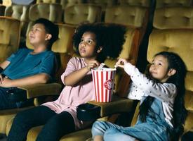 diversité groupe d'enfants afro-américains et asiatiques regardant un film au théâtre ensemble. photo