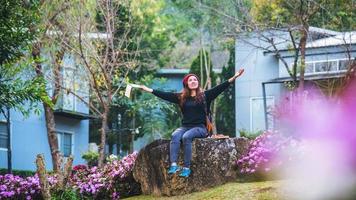 femme voyage nature dans le jardin fleuri. détendez-vous assis sur des rochers et lisez des livres au milieu de la nature au parc national doi inthanon. photo