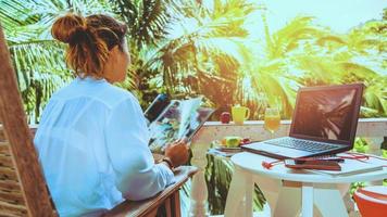 femme assise sur une chaise voir des magazines. pendant les vacances restez à la maison. photo