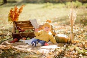 jolie petite fille assise sur une citrouille et jouant dans la forêt d'automne photo