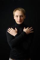 portrait d'un homme beau et déterminé portant une chemise noire, fond noir. photo