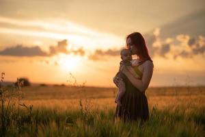 une mère tient tendrement son fils de trois mois dans ses bras dans un champ de blé. photo