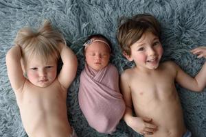 deux frères s'allongeront à côté de sa sœur nouveau-née. photo