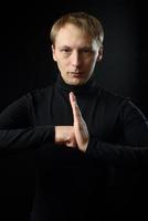 portrait d'un homme beau et déterminé portant une chemise noire, fond noir. photo