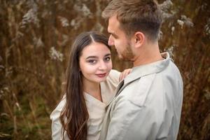 jeune couple amoureux se tenant la main et se promenant dans un parc par une journée ensoleillée d'automne photo